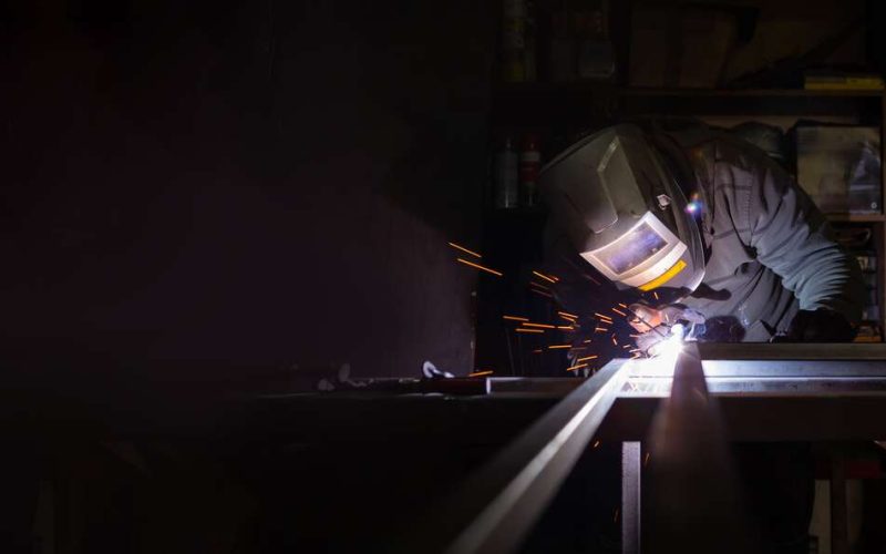 Worker With Welding Machine in His Hand and Welds the Metal Structure